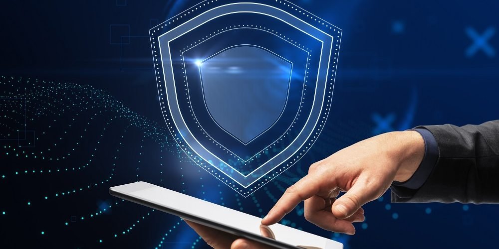 Mão do empresário apontando para o smartphone com holograma de escudo brilhante criativo simbolizando a proteção de dados