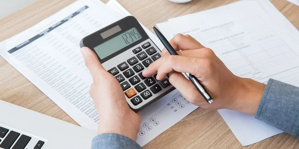 Pessoa com uma calculadora, calculando a tributação para provedores de internet.